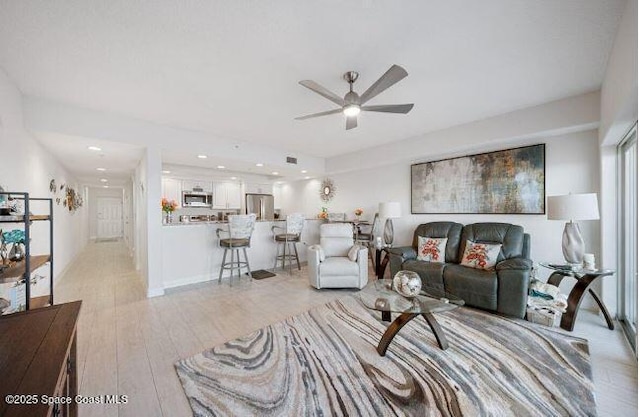 living room with light hardwood / wood-style floors and ceiling fan