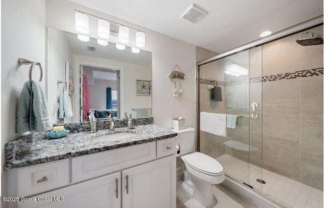 bathroom featuring vanity, a shower with shower door, a textured ceiling, and toilet