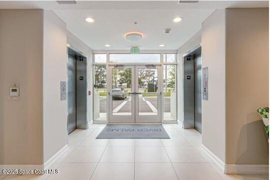 entrance foyer featuring light tile patterned floors, a wall of windows, french doors, and elevator