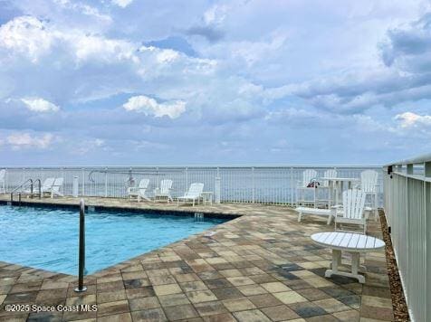 view of swimming pool with a patio area and a water view