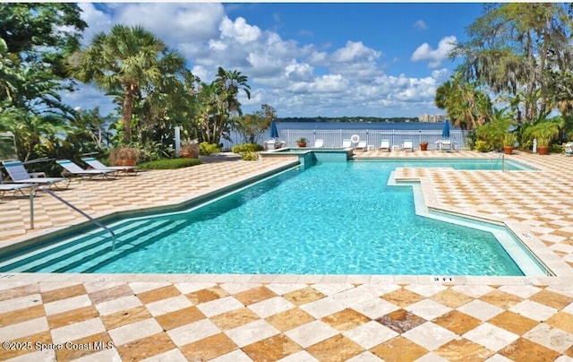 view of pool with a patio and a water view