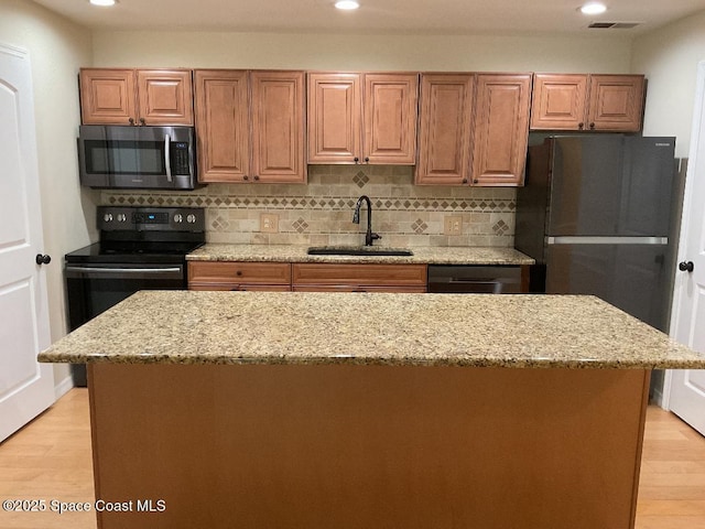 kitchen with light stone counters, backsplash, sink, and black appliances