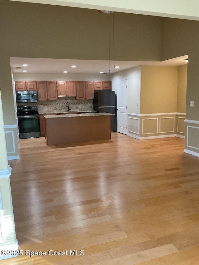 kitchen featuring light hardwood / wood-style flooring, black refrigerator, hanging light fixtures, electric range, and a center island