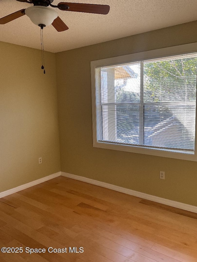 empty room featuring ceiling fan, light hardwood / wood-style floors, and a textured ceiling