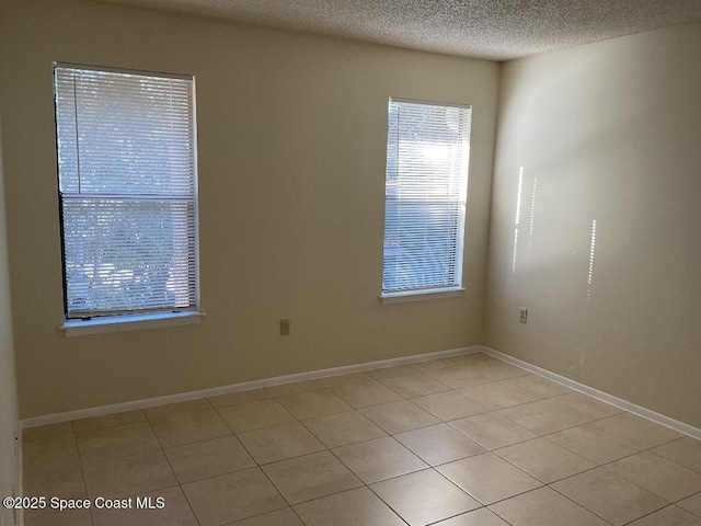 unfurnished room with a textured ceiling and light tile patterned floors