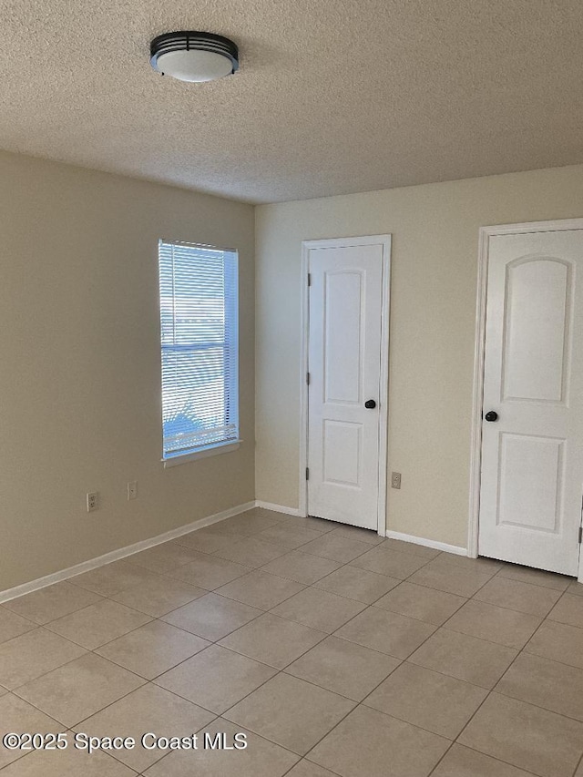 unfurnished room featuring a textured ceiling and light tile patterned floors