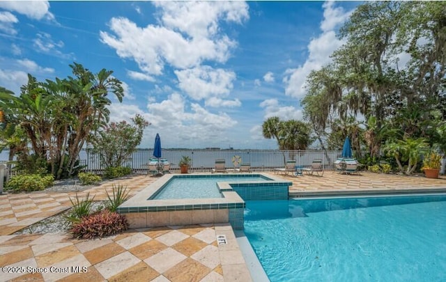 view of pool featuring a water view, a patio area, and a jacuzzi