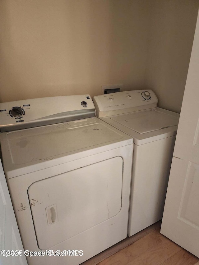 washroom with washer and clothes dryer and light hardwood / wood-style flooring