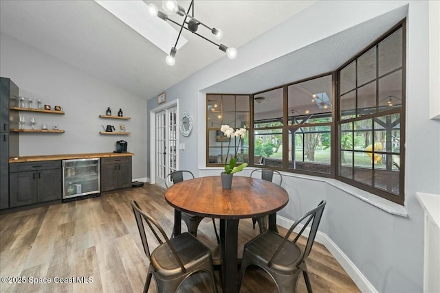 dining room with wood-type flooring, lofted ceiling, bar area, and beverage cooler