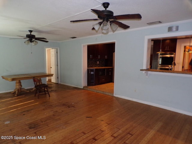 unfurnished living room featuring wood-type flooring, ornamental molding, and ceiling fan