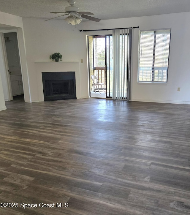 unfurnished living room featuring ceiling fan, dark hardwood / wood-style floors, and a textured ceiling