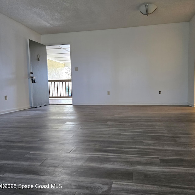 empty room with dark hardwood / wood-style floors and a textured ceiling