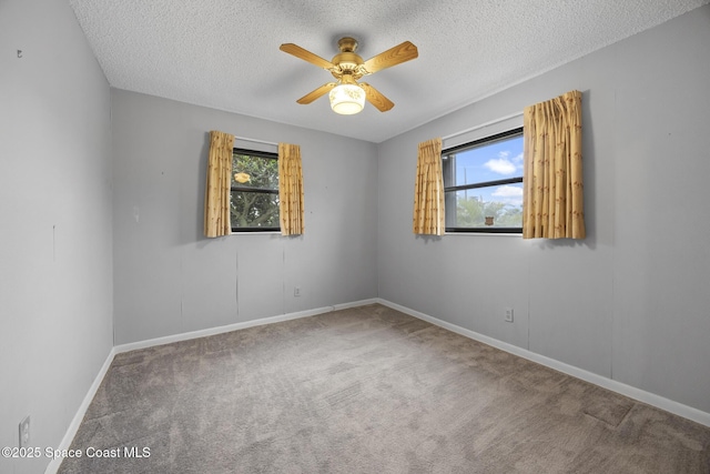 carpeted spare room with ceiling fan, a healthy amount of sunlight, and a textured ceiling