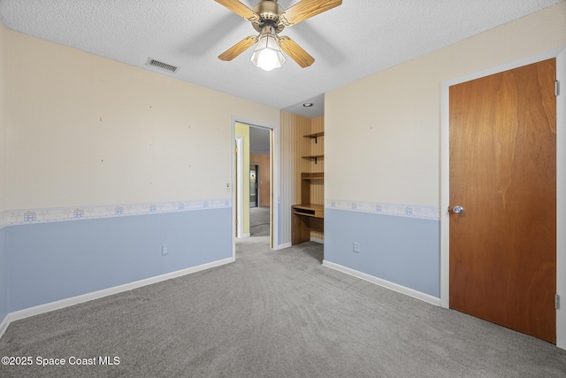 unfurnished bedroom with ceiling fan, light carpet, and a textured ceiling