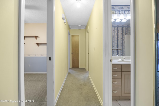 hallway featuring sink, light colored carpet, and a textured ceiling