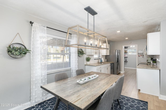 dining room featuring sink, light hardwood / wood-style flooring, and a textured ceiling