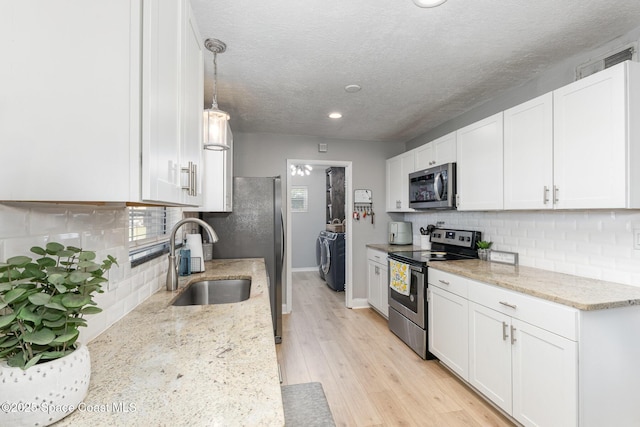 kitchen with sink, white cabinetry, a textured ceiling, appliances with stainless steel finishes, and light stone countertops