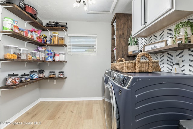 laundry area featuring cabinets, light hardwood / wood-style floors, and washing machine and dryer