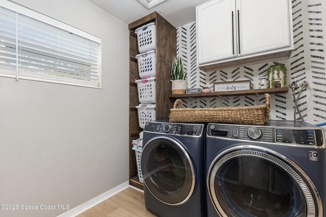 washroom with cabinets, washing machine and clothes dryer, and light wood-type flooring