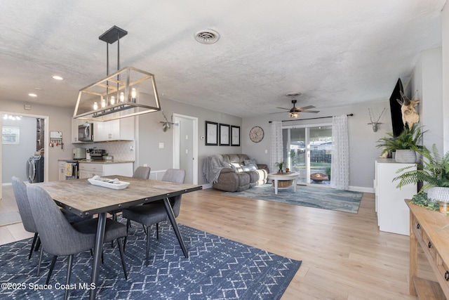 dining area featuring wood-type flooring, ceiling fan, and a textured ceiling