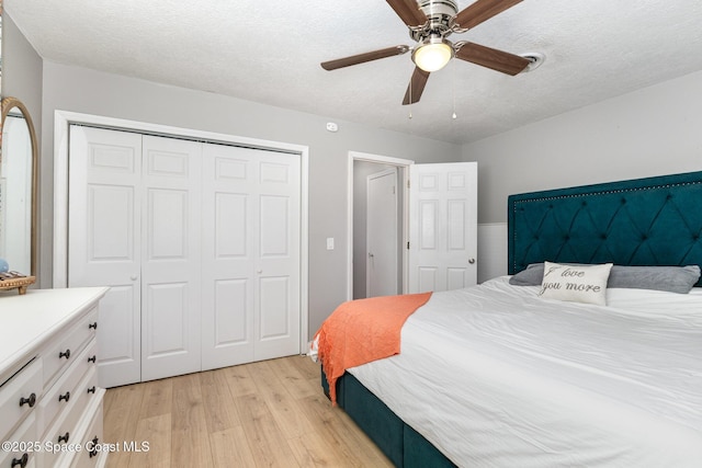 bedroom with light wood-type flooring, a textured ceiling, ceiling fan, and a closet