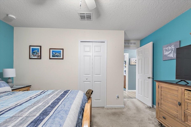 bedroom featuring light carpet, a textured ceiling, ceiling fan, and a closet