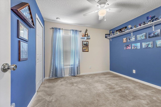 unfurnished room featuring ceiling fan, light colored carpet, and a textured ceiling