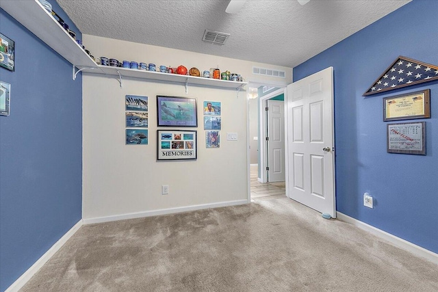 spare room featuring ceiling fan, light colored carpet, and a textured ceiling