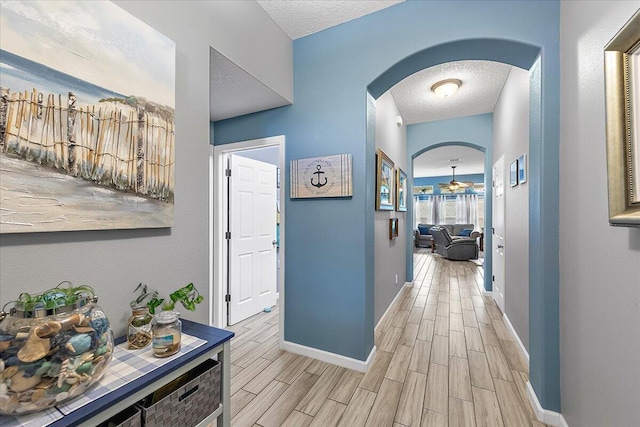 hallway with light hardwood / wood-style flooring and a textured ceiling