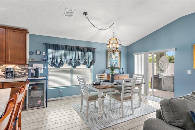 dining area with wine cooler, vaulted ceiling, a textured ceiling, and an inviting chandelier