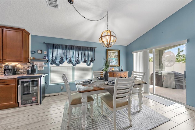 dining area with lofted ceiling, plenty of natural light, wine cooler, and a chandelier