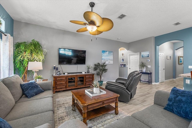 living room with ceiling fan, light hardwood / wood-style flooring, and a textured ceiling