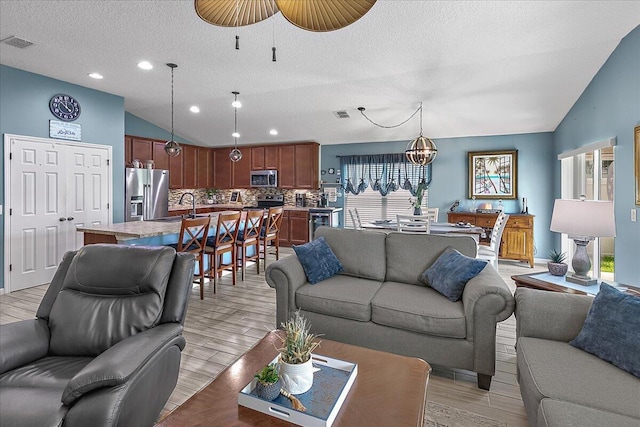 living room with plenty of natural light, sink, vaulted ceiling, and a textured ceiling