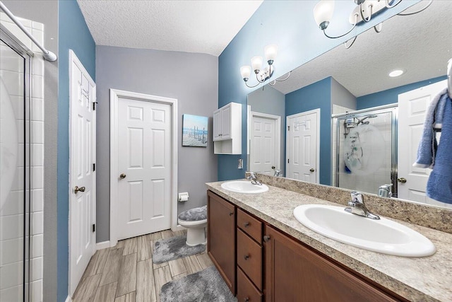 bathroom with walk in shower, vanity, toilet, and a textured ceiling