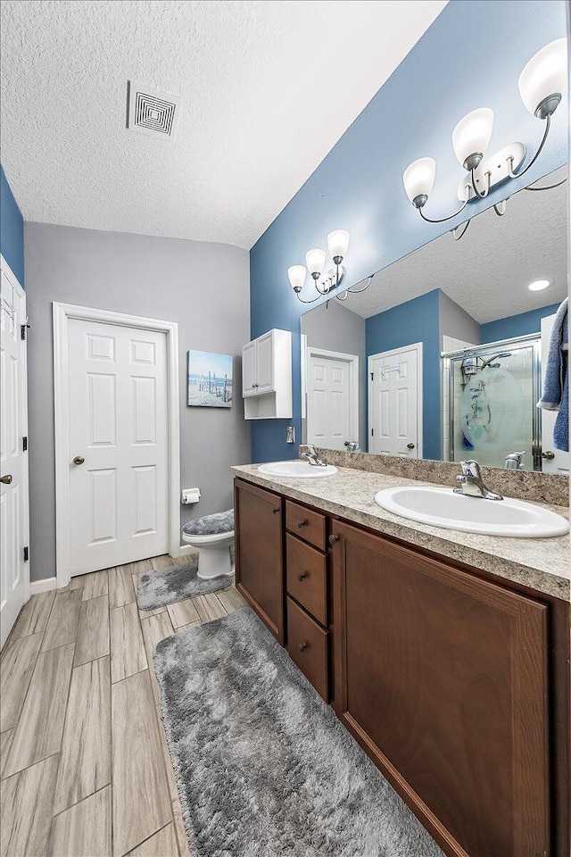 bathroom featuring a shower with shower door, vanity, a notable chandelier, toilet, and a textured ceiling