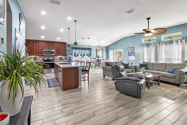 living room featuring lofted ceiling, sink, a textured ceiling, and a wealth of natural light