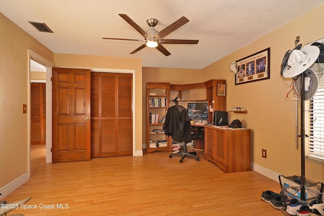 office area featuring light wood-type flooring, visible vents, a textured ceiling, and baseboards