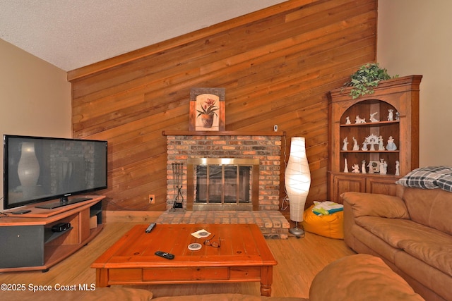 living room featuring a fireplace, wood walls, a textured ceiling, and wood finished floors