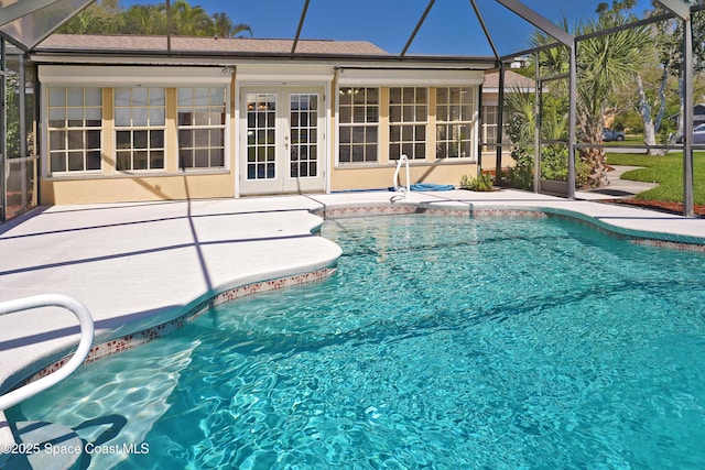 pool with a lanai, a patio area, and french doors