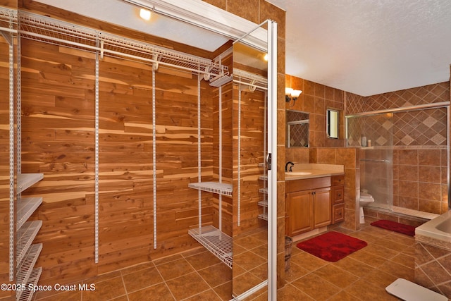 full bathroom featuring tile patterned flooring, toilet, vanity, tile walls, and a stall shower