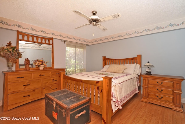 bedroom with a ceiling fan, light wood-style flooring, and a textured ceiling