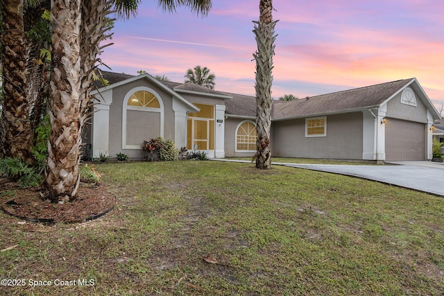 single story home featuring a garage and a yard