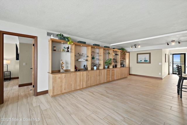 bar featuring light hardwood / wood-style floors and a textured ceiling