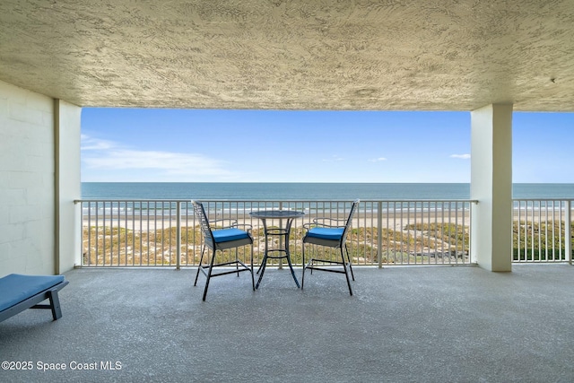 balcony featuring a water view and a beach view