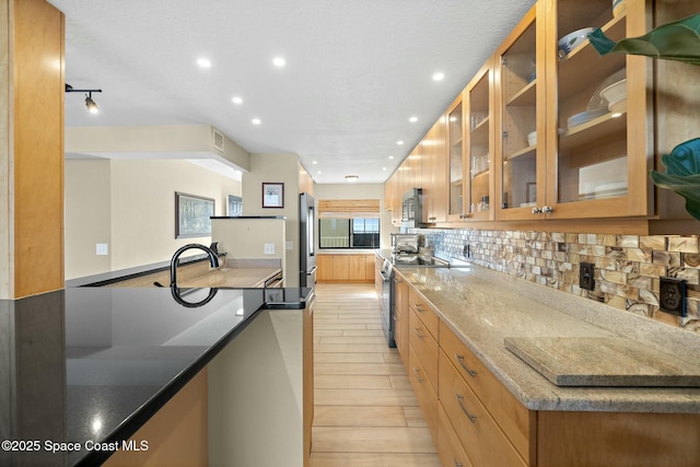 kitchen featuring stainless steel appliances, tasteful backsplash, and light stone counters