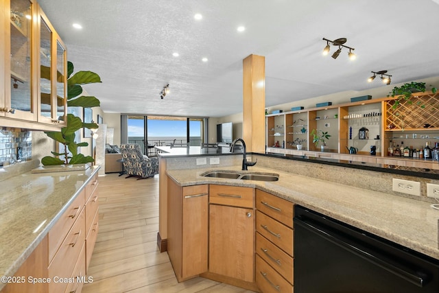 kitchen featuring sink, light stone counters, black dishwasher, kitchen peninsula, and light hardwood / wood-style floors