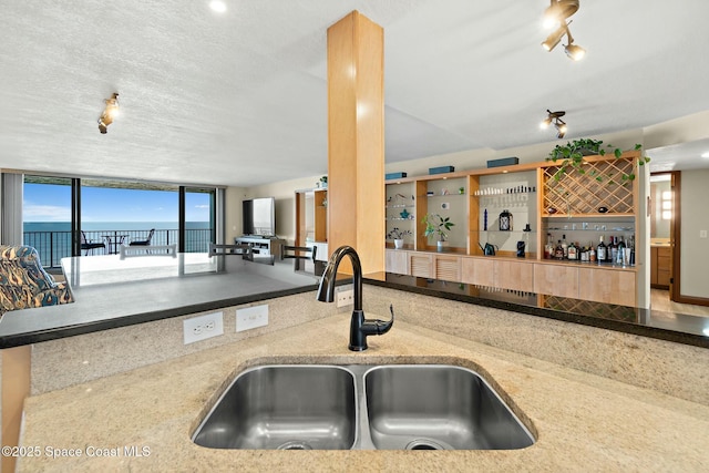 kitchen with a water view, sink, and a textured ceiling