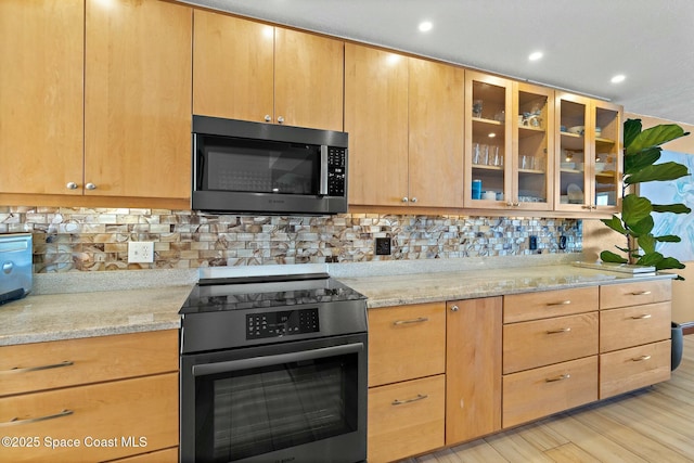 kitchen with electric stove, decorative backsplash, light stone countertops, light brown cabinets, and light hardwood / wood-style flooring