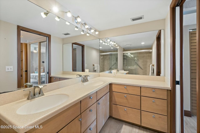 bathroom featuring a shower with door and vanity