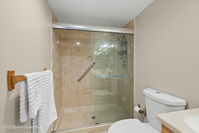 bathroom featuring vanity, a shower with shower door, and toilet